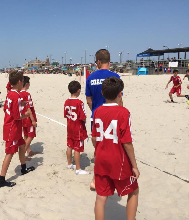 Trainer-Coaching der Fußballspieler auf einem Beach Soccer Feld